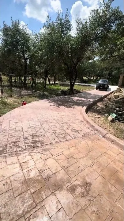 Finished stamped and colored concrete driveway curving through the San Marcos property